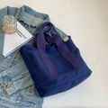 Minimalistische dunkelblaue Canvas-Tragetasche mit braunem Lederetikett auf Denim - Blau