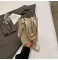 Gros plan d'un sac seau en cuir grainé beige avec poignée supérieure et bandoulière - Blanc Cassé