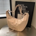 Sac hobo beige chic avec nœud et bandoulière réglable sur une table en métal - Rose