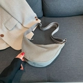 Bolso medialuna de pana gris con correa ajustable sobre un sofá de tela gris - Gris