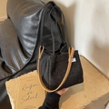 Fashionable black denim bucket bag with brown leather handles on a natural stone base - Black