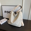 Borsa a tracolla minimalista in tela crema con ampia tracolla su tavolo in legno - Bianco Sporco