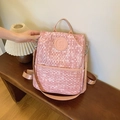 Rosa Rucksack mit Webstruktur und Bären-Logo auf Holzoberfläche mit Tragegriff oben - Rosa
