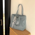 Light blue denim tote bag with white lace bow and embroidery on a woven basket - Blue