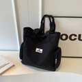 Black canvas tote bag featuring functional side zippers and a fashion brand label - Black