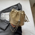 Champagne gold drawstring bucket bag with silver metal chain on a grey blazer - Gold