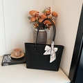 Large black woven tote bag with a floral scarf detail in a minimalist setting - Black