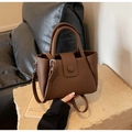 Close-up of brown litchi pattern leather handbag on a stone surface with soft lighting - Brown