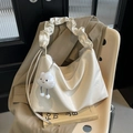 Chic beige pleated hobo tote bag with cloud strap and plush charm on a chair - With Cloud Pendant / Off White