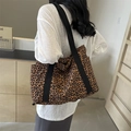 Bolso tote grande de lona con estampado de leopardo y asas negras llevado por modelo - Marrón