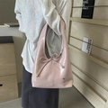 Pink glossy patent leather tote bag with bow detail shown on shoulder in a chic interior - Pink