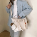 Creamy white nylon tote bag with small zipper pouch shown on model in a minimalist setting - White