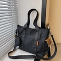 Black nylon tote bag with orange label, mini coin pouch, and brown leather pocket detail - Black