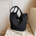 Borsa tote in denim grigio scuro con logo dorato su una superficie in pietra ruvida - Nero