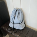 Hellblauer Nylon-Kordelzug-Rucksack mit grauer Netztasche auf einer braunen Lederbank - Blau Ohne Anhänger