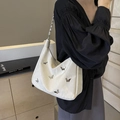White embossed underarm bag with silver butterfly charms and metal chain strap worn by model - Large / Off White