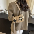 Stroh-Hobo-Tasche mit Sternen und Silberkette, getragen von einem Modell im Café - Khaki