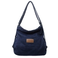 Large capacity dark blue denim shoulder bag with brown leather logo patch on white background - Dark Blue