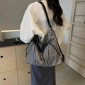 Grande borsa grigia con motivo a cuori e fiocco indossata da modella in posa - Cuore