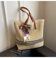 Detail of straw woven tote with black stripes and silk scarf on a leather sofa - Off White