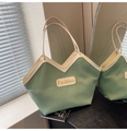 Detalle de bolso tote verde plisado con borde crema y asas dobles en superficie reflectante - Verde