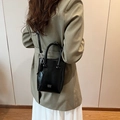 Glänzende schwarze Beuteltasche aus Lackleder mit silbernem Logo und Schultergurt - Schwarz