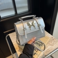 Silver metallic crossbody bag with butterfly ornament and sleek top handle style - Silver