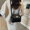 Chic black crossbody bag with silver butterfly buckle shown on a female model - Black