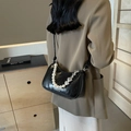Chic black crescent underarm bag with pearl strap and silver heart charms shown on model - Black