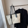 Elegante borsa tote beige con trama vintage e spalline nere appesa a una gruccia - Bianco Sporco