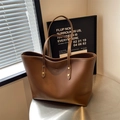 Bolso tote de cuero marrón con logo Bolleda sobre mesa de metal en estilo moderno - Marrón
