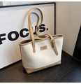 Gros plan des coutures contrastées et du logo en cuir sur un sac cabas beige - Blanc Cassé