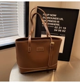 Détails d'un cabas en cuir marron avec surpiqûres blanches et plaque logo élégante - Marron