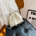 Bolso saco blanco con cordón, lazos y cadena plateada sobre un cojín de cuero negro - Blanco Roto Pequeño