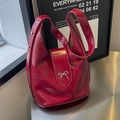 Glossy red leather bucket bag with silver bow accent and studded wide shoulder strap - Burgundy