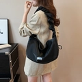 Borsa a mezzaluna nera a pieghe in nylon effetto seta indossata con tailleur beige - Nero