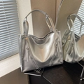 Detalle del bolso tote plateado metalizado con cremalleras sobre una base de madera - Plateado
