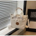 Dettaglio della borsa tote in tela bianca con logo in pelle marrone e tracolla regolabile - Bianco Sporco
