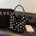 Black tote bag with white number patterns and a decorative bow on a leather sofa - Black