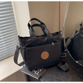 Dettaglio della borsa a tracolla in nylon nero con logo in pelle e finiture argentate - Nero