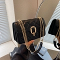 Detailed view of the black quilted crossbody bag showing golden chain and lock - Black