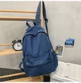 Détail du sac à dos en jean bleu montrant la texture délavée et la poche frontale - Bleu foncé