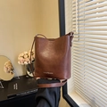 Minimalistische tiefbraune Eimer-Tasche aus Kunstleder mit Riemen in Retro-Atmosphäre - Braun