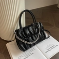 Black pleated handbag with chunky silver chain on modern art book backdrop - Black
