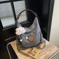 Detailansicht der Canvas-Tasche mit Lederriemen und silbernem M-Logo-Anhänger - Denimblau mit Anhänger
