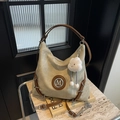 Detail der beigefarbenen Hobo-Tasche mit M-Metalllogo und flauschigem Wolkenanhänger - Beige Mit Anhänger