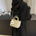 Mini beige bucket bag with plush charm, lychee grain leather finish, worn as crossbody bag - With Charm / Off White