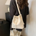 Off-white bucket bag met zilveren vlinder en trekkoordsluiting gedragen door model - Wit