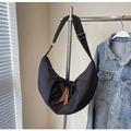 Detail of nylon dumpling bag featuring brown leather zipper pulls and adjustable strap - Black
