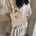 Sac bandoulière texturé beige orné d'une grande boucle papillon en métal argenté - Beige